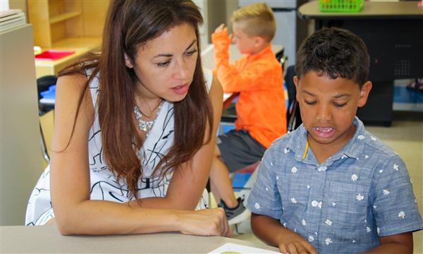 A woman works with a boy at a desk